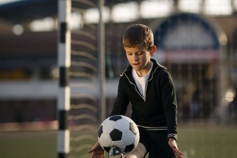 boy-plays-football-on-stadium.jpg